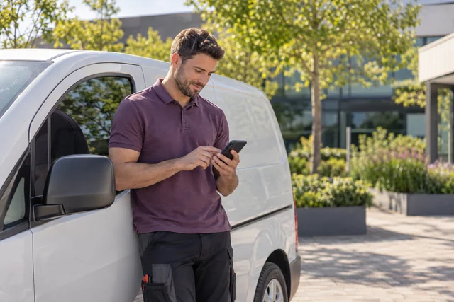 Employee recording work travel details beside a parked van