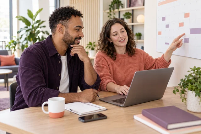 Colleagues reviewing time off dates on a workplace calendar
